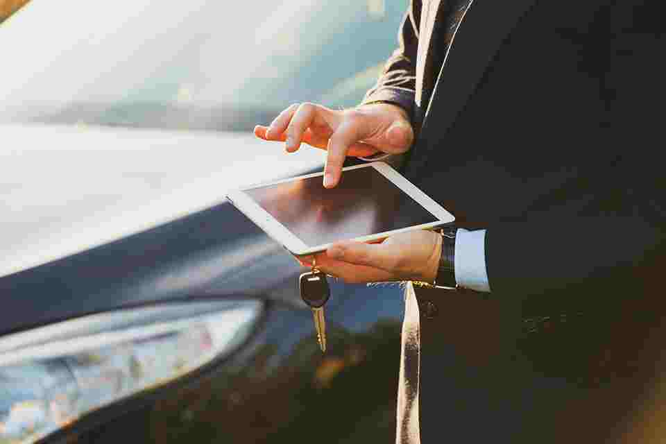 Person bedient Smartphone vor Auto